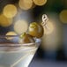 A Belosa martini with Queen olives on a table.