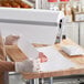 A person in a white apron using Choice Premium Freezer Paper to wrap meat on a cutting board.