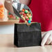 A person holding a black American Metalcraft mini snack bag filled with candies.