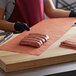 A person cutting sausages on a table with PeachTREAT steak paper.