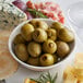 A white plate with Belosa jalapeno stuffed green olives and cheese.