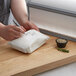 A person using a knife to cut food on a roll of Choice White Butcher Paper.