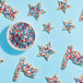 A bowl of star-shaped cookies with white frosting and Adourne red, white, and blue sprinkles.