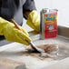 A person in yellow gloves using a brush to clean a surface with Carbon-Off.