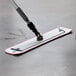 A person using a red Lavex microfiber spray mop to clean a floor.