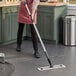 A woman using a Lavex pink microfiber spray mop to clean the floor.