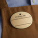 A brown apron with a gold oval Cawley nametag on it.