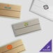 A white rectangular Cawley metal nametag with a logo on it.