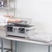 A woman using a white Cambro food pan carrier with black handles to hold a large container.