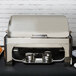 A Vollrath silver New York roll top chafer on a table with food inside.