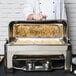 A chef using a Vollrath New York Roll Top Chafer on a hotel buffet table.