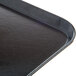 A close up of a Dinex black Glasteel fiberglass tray with a black plastic handle.