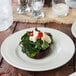 An ivory embossed rim china bread and butter plate with a mushroom, spinach, and cheese dish.