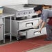 A woman in a chef's hat opening an Avantco refrigerated drawer.