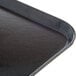 A close up of a black Dinex Glasteel fiberglass tray with black handles.