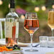 A Libbey Tritan plastic wine glass filled with wine on a table with fruit.