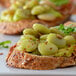 A plate of green beans on a table with bread and cheese.