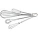A group of four Fox Run metal whisks on a white background.