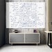 A Luxor magnetic glass whiteboard with math equations on it and books on a grey cabinet.