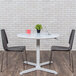 A white Luxor round pneumatic adjustable height table with a laptop and a potted plant on it.