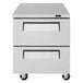 A stainless steel Turbo Air undercounter refrigerator with two drawers on wheels.