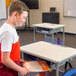 A boy standing at a Luxor student standing desk with a book.