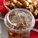 A plastic cup with a drink in it next to a bowl of fries with a Solo PET plastic lid on it.