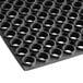 A close up of a Lavex black rubber anti-fatigue floor mat with holes.