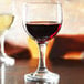 An Anchor Hocking Excellency wine glass filled with red wine sits on a table.