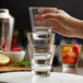 A person holding a Libbey stackable rocks glass full of water.