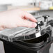 A hand holding a lid to a black container.