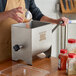 A person using a Backyard Pro meat mixer to mix red pepper into a metal container.