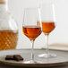 A close-up of a Stolzle Spirit Taster glass filled with brown liquid.
