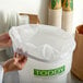 A hand holding a Toddy commercial cold brew strainer over a container with a white plastic bag inside.