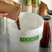 A person using a Toddy commercial cold brew paper filter to pour coffee into a container.