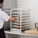 A man using a Regency countertop sheet pan rack to cook cookies.