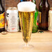 A WNA Comet plastic pilsner cup filled with beer on a table with other bottles.