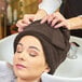 A woman with a brown Monarch Brands hand towel on her head.