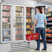 A woman standing in front of a Beverage-Air white glass door merchandiser freezer.