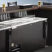 A black Beverage-Air deep well bottle cooler on a counter with drinks on top.