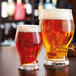 Two Arcoroc Barlow Pilsner glasses filled with beer on a table.