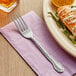 A plate with a Choice stainless steel dinner fork on a napkin next to food.