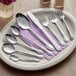 Choice Bethany stainless steel serving spoon on a plate with silverware.