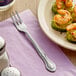 A plate of food with shrimp and a Choice stainless steel oyster/cocktail fork on it.