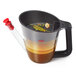 An OXO Good Grips fat separator with a brown liquid in it.