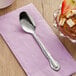 A Choice Bethany stainless steel teaspoon on a napkin next to a bowl of chocolate dessert.