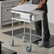 A man using a Metro PrepMate Small Chopped Ingredient Prep Multistation on a white table.