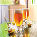 Arcoroc Cervoise stemmed Pilsner glasses filled with beer on a table.