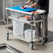 A man using the Metro PrepMate Seafood Prep Multistation to cut raw salmon on a blue cutting board.