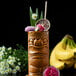 A tiki drink with a flower and a straw in a tiki glass.